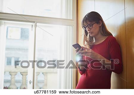 Stock Photo - Businesswoman looking at smartphone in office. Fotosearch