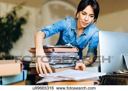 Businesswoman looking through files on desk View Large Photo Image Stock Photograph - Businesswoman looking through files on desk. Fotosearch