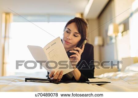 Stock Photo - Businesswoman ordering room service in hotel. Fotosearch