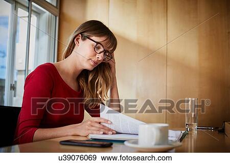 Businesswoman reading paperwork at boardroom table View Large Photo Image Stock Photo - Businesswoman reading paperwork at boardroom table. Fotosearch