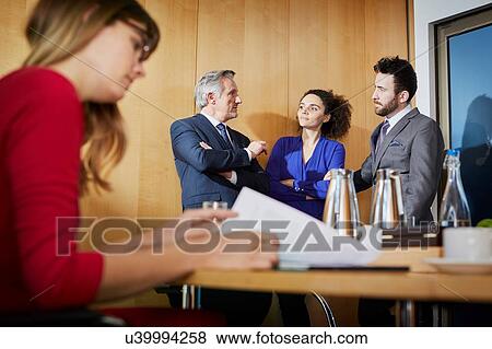 Stock Photo - Businesswoman reading paperwork at boardroom table during meeting. Fotosearch