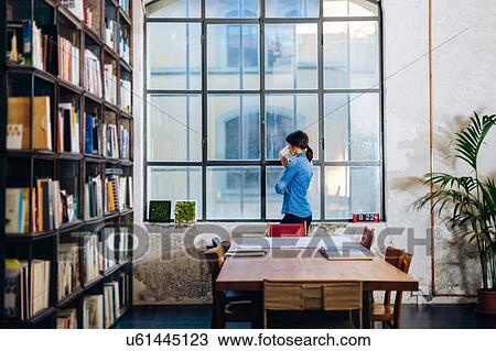 Businesswoman standing beside window, drinking from disposable coffee cup View Large Photo Image Stock Image - Businesswoman standing beside window, drinking from disposable coffee cup. Fotosearch