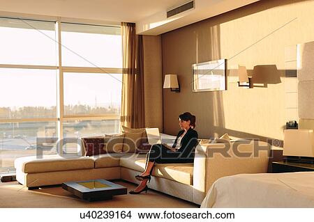 Businesswoman using laptop in lounge area of hotel bedroom View Large Photo Image Picture - Businesswoman using laptop in lounge area of hotel bedroom. Fotosearch