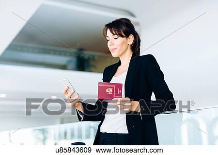Stock Photo - Businesswoman using mobile phone for electronic check-in. Fotosearch