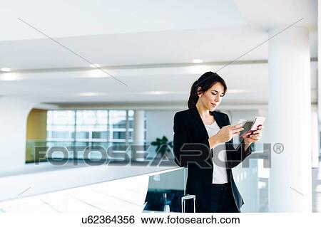 Stock Photograph - Businesswoman using mobile phone for electronic check-in. Fotosearch