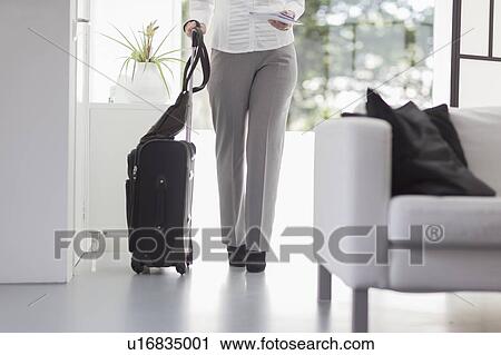 Stock Image - Businesswoman walking with suitcase. Fotosearch