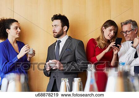 Stock Photo - Businesswomen and men chatting before office meeting. Fotosearch