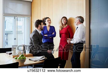 Stock Image - Businesswomen and men having office meeting. Fotosearch