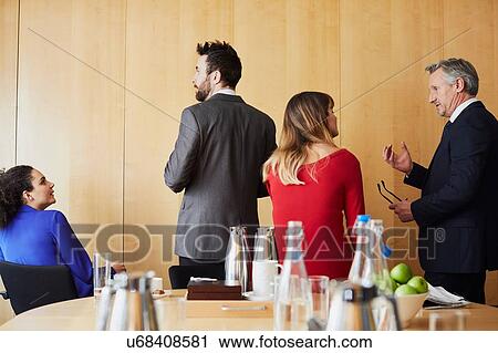 Stock Image - Businesswomen and men taking a break during office meeting. Fotosearch