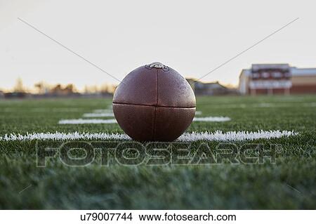 Picture - Close up of American football ball on green playing field. Fotosearch