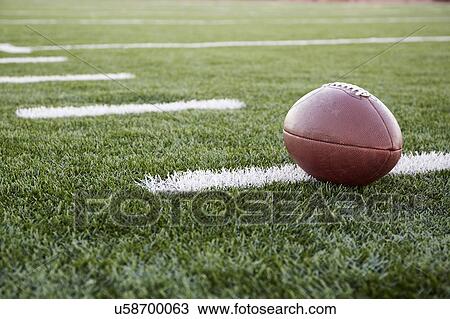 Close up of American football ball on green playing field View Large Photo Image Stock Image - Close up of American football ball on green playing field. Fotosearch
