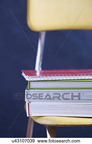 Stock Photo - Close up of books stacked on chair. Fotosearch