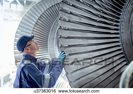 Stock Photograph - Close up of engineer inspecting low pressure turbine during inspection in turbine maintenance factory. Fotosearch