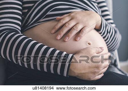 Close-up of pregnant woman with hands on abdomen. View Large Photo Image Picture - Close-up of pregnant woman with hands on abdomen.. Fotosearch