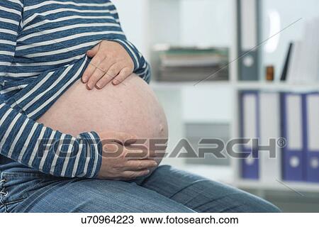 Stock Image - Close-up of pregnant woman with hands on abdomen... Fotosearch