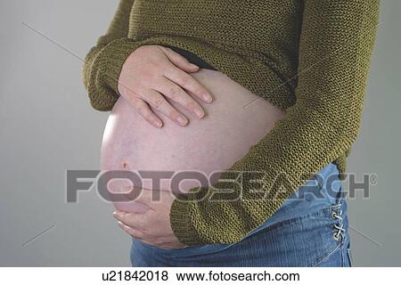 Stock Photo - Close-up of pregnant woman with hands on abdomen.. Fotosearch