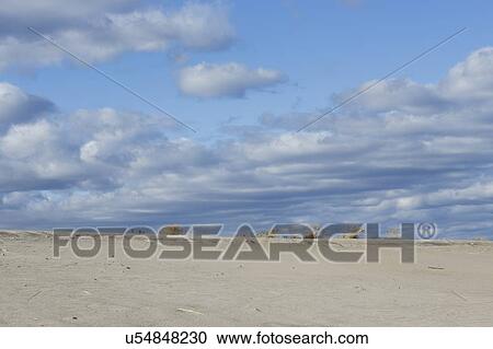 Stock Image - Clouds over sand dunes on beach. Fotosearch