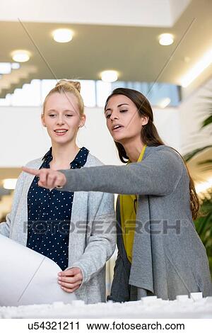 Colleagues discussing town planning drawings in office View Large Photo Image Stock Image - Colleagues discussing town planning drawings in office. Fotosearch