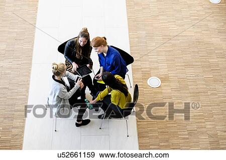 Stock Photo - Colleagues having meeting using digital tablet. Fotosearch