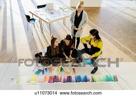 Picture - Colleagues sitting on floor working with colour swatches. Fotosearch