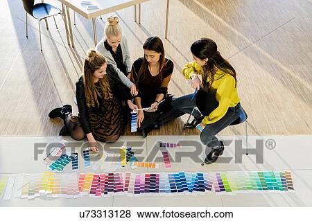 Stock Photo - Colleagues sitting on floor working with colour swatches. Fotosearch