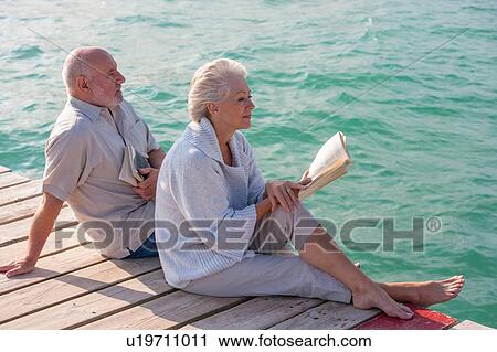 Couple enjoying seaside from jetty View Large Photo Image Stock Image - Couple enjoying seaside from jetty. Fotosearch