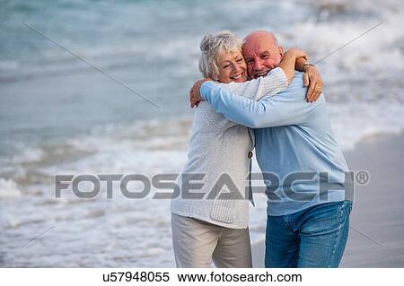 Stock Photography - Couple hugging and laughing by seaside. Fotosearch