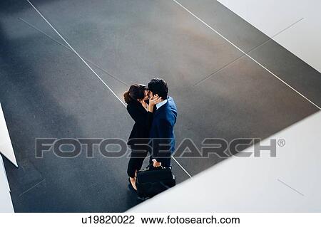 Stock Image - Couple in business suits kissing. Fotosearch