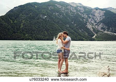 Stock Image - Couple in shallow water kissing, Achensee, Innsbruck, Tirol, Austria, Europe. Fotosearch