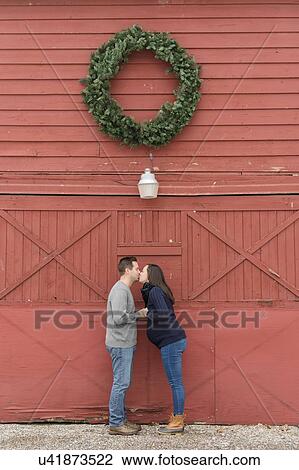 Couple kissing below wreath View Large Photo Image Stock Image - Couple kissing below wreath. Fotosearch
