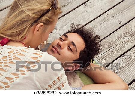 Couple lying face to face on decking View Large Photo Image Stock Image - Couple lying face to face on decking. Fotosearch