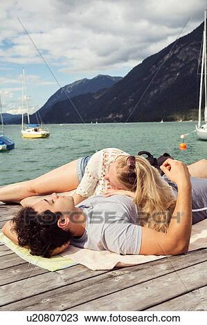 Stock Image - Couple lying together on pier, Innsbruck, Tirol, Austria, Europe. Fotosearch