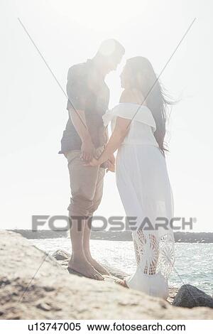 Couple standing on coastal rocks, holding hands, face to face, Seal Beach, California, USA View Large Photo Image Stock Photography - Couple standing on coastal rocks, holding hands, face to face, Seal Beach, California, USA. Fotosearch
