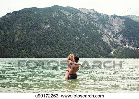 Stock Image - Couple waist deep in water kissing, Achensee, Innsbruck, Tirol, Austria, Europe. Fotosearch