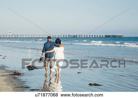 Couple walking along beach, barefoot, rear view, Seal Beach, California, USA View Large Photo Image Stock Photo - Couple walking along beach, barefoot, rear view, Seal Beach, California, USA. Fotosearch
