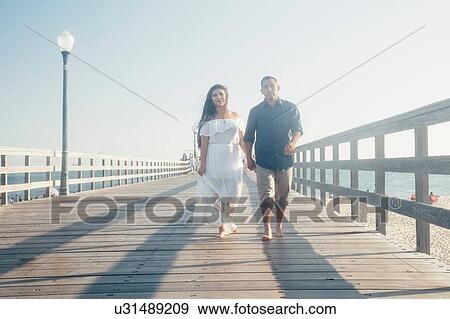 Couple walking along pier, holding hands, Seal Beach, California, USA View Large Photo Image Stock Photo - Couple walking along pier, holding hands, Seal Beach, California, USA. Fotosearch