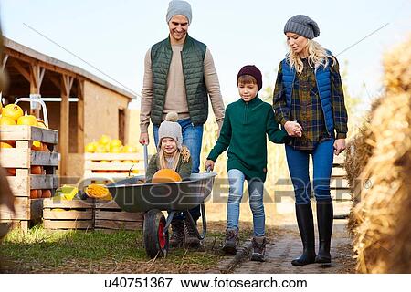 Stock Photo - Couple with son and daughter in wheelbarrow at pumpkin patch. Fotosearch