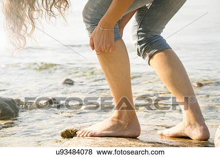 Stock Photo - Cropped view of woman barefoot on rocks. Fotosearch
