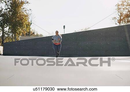 Curvaceous young female runner running in urban setting View Large Photo Image Stock Image - Curvaceous young female runner running in urban setting. Fotosearch