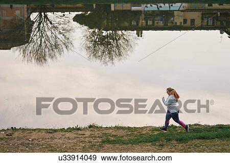 Curvaceous young female runner running on riverside View Large Photo Image Stock Photo - Curvaceous young female runner running on riverside. Fotosearch