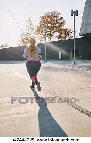 Stock Photo - Curvaceous young female runner running, rear view. Fotosearch