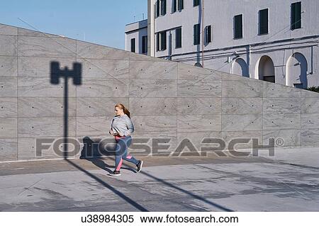 Curvaceous young female runner running along sidewalk View Large Photo Image Stock Photography - Curvaceous young female runner running along sidewalk. Fotosearch