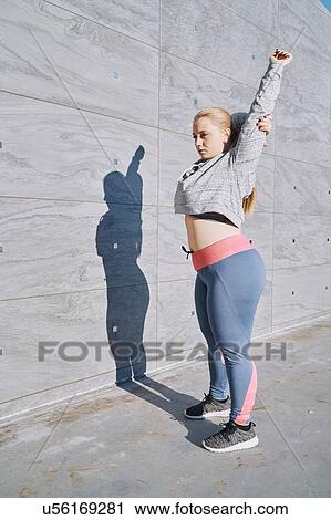 Stock Image - Curvaceous young woman training, stretching arms. Fotosearch