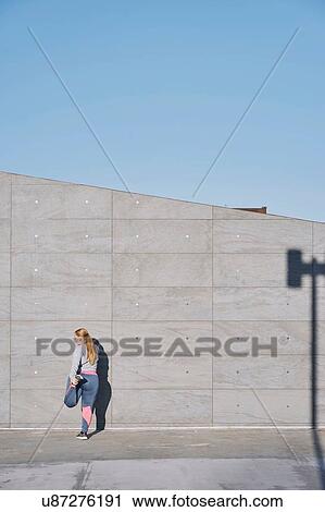 Stock Image - Curvaceous young woman training, stretching leg. Fotosearch