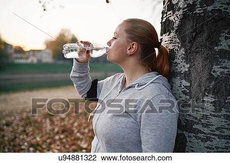 Curvaceous young woman training, drinking bottled water in park View Large Photo Image Stock Image - Curvaceous young woman training, drinking bottled water in park. Fotosearch
