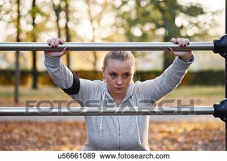 Stock Photo - Curvaceous young woman training, leaning against handrail in park. Fotosearch
