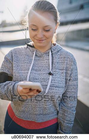 Curvaceous young woman training, looking at smartphone View Large Photo Image Stock Photo - Curvaceous young woman training, looking at smartphone. Fotosearch