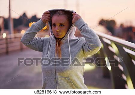 Curvaceous young woman training, getting hoody ready on footbridge at dusk View Large Photo Image Stock Photo - Curvaceous young woman training, getting hoody ready on footbridge at dusk. Fotosearch