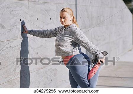 Stock Photograph - Curvaceous young woman training, stretching leg. Fotosearch