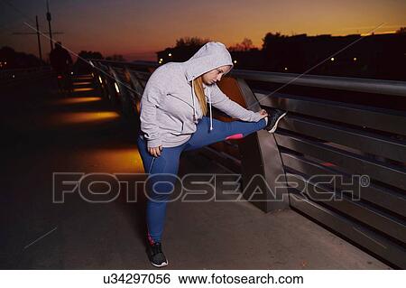 Curvaceous young woman training, touching toes on footbridge at night View Large Photo Image Stock Photograph - Curvaceous young woman training, touching toes on footbridge at night. Fotosearch